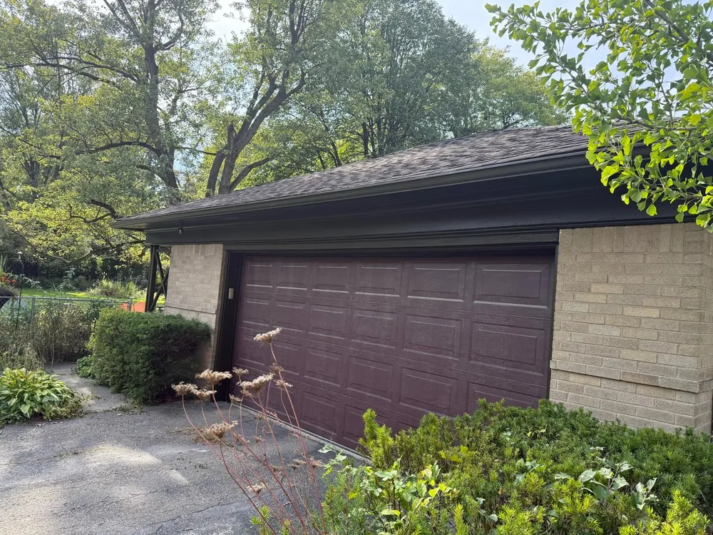Bronze garage door and fascia against unpainted pale brick on a ranch home