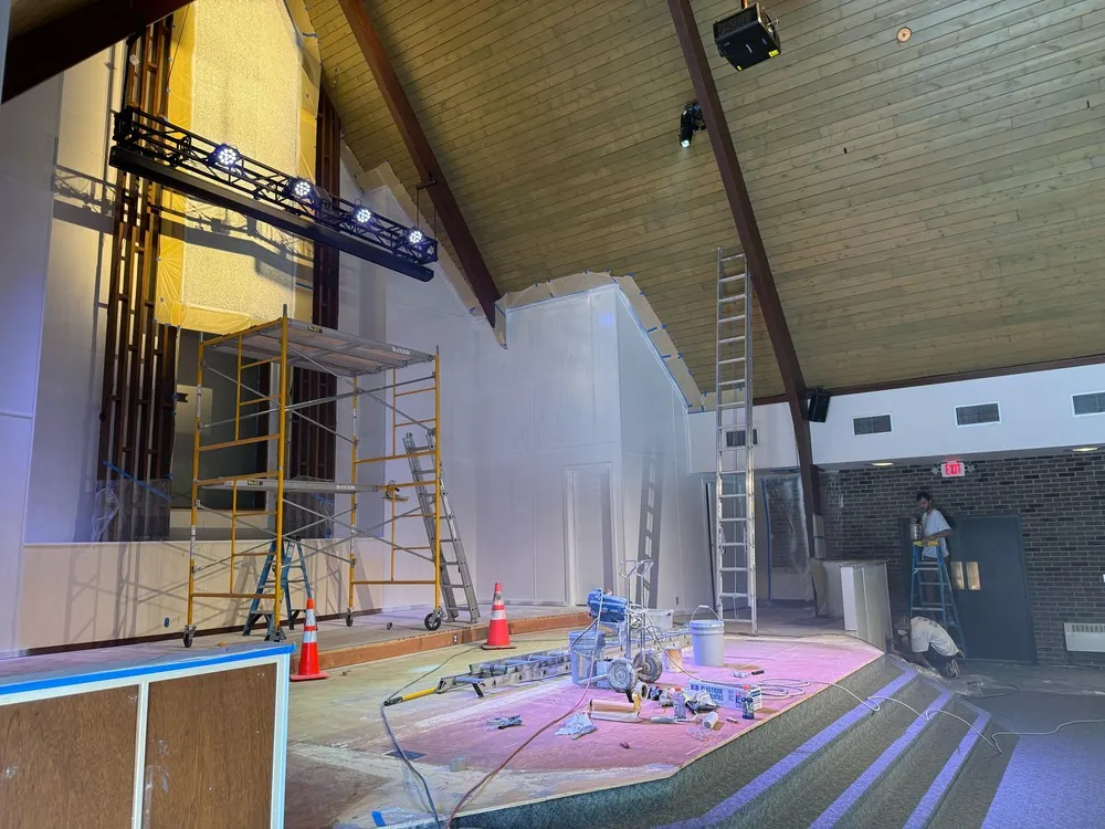 Scaffolding, ladders and floor protection arranged in a church sanctuary during painting