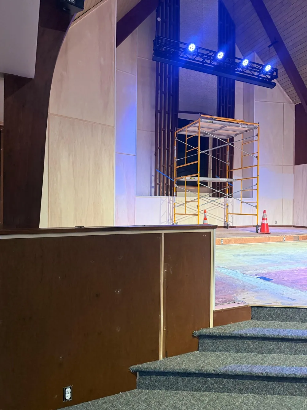 Partly coated church wall panels beside scaffolding and taped floor edges