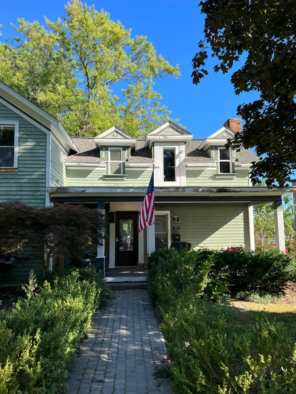 Front walk leading to a freshly painted sage farmhouse