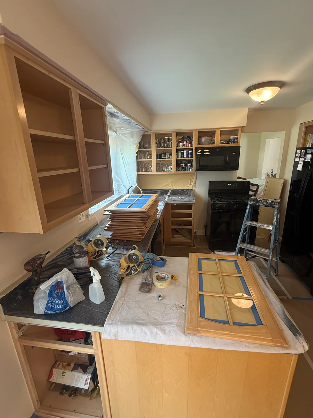 Removed glass cabinet doors with masked panes beside open wood cabinet boxes