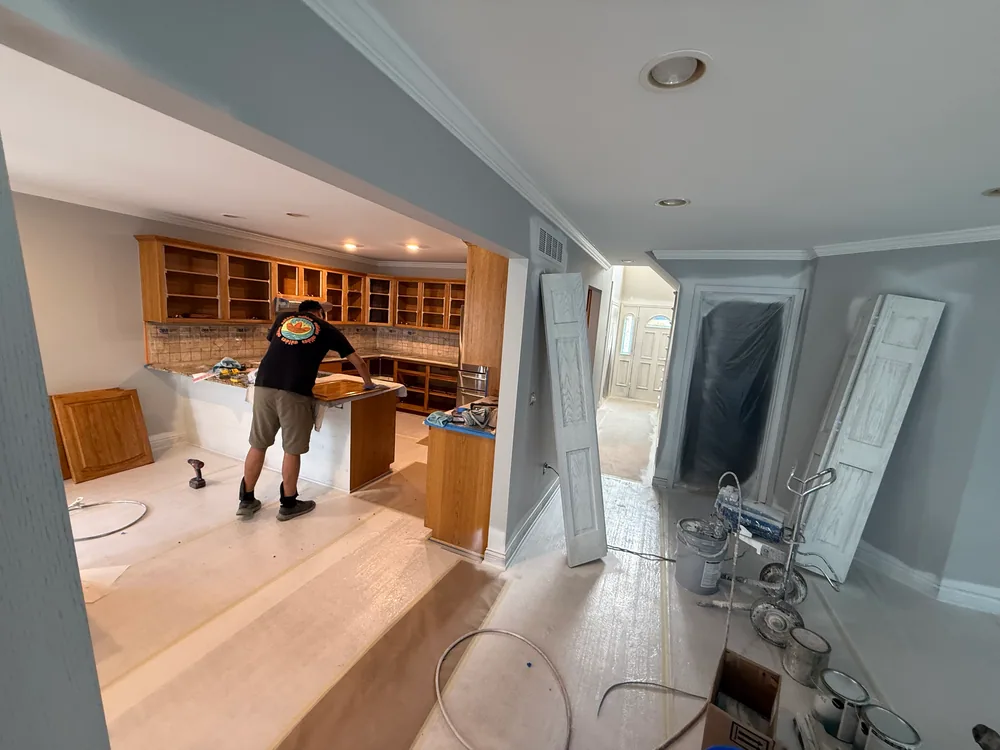 Worker manually preparing a removed cabinet door in a protected interior work area