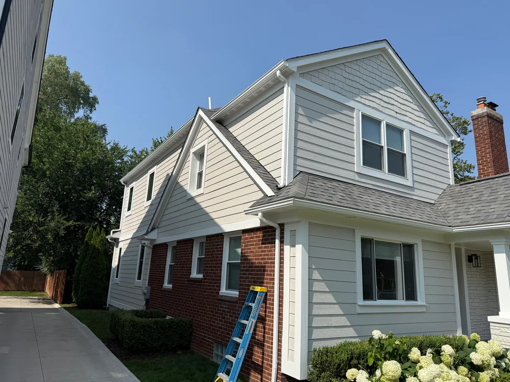 Light-colored siding and white trim on a gabled house with a ladder still in place.