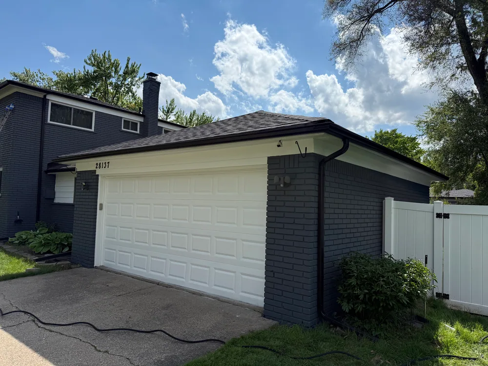 White garage door framed by dark gray brick and light trim