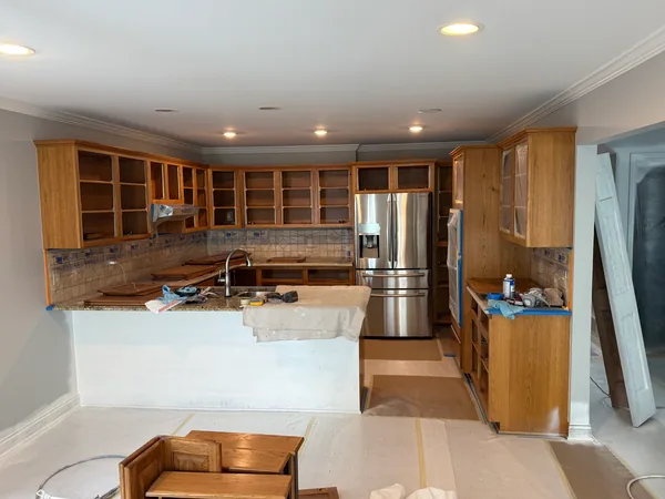 Open wood cabinet boxes with masked backsplash, covered flooring and removed fronts