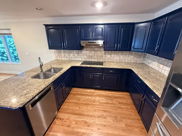 Dark blue cabinet doors with metal handles, a beige tile backsplash and clear countertops