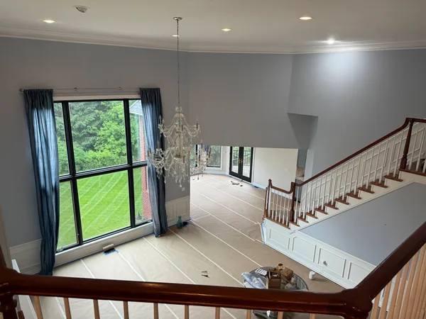 Tall windows above a living room floor covered with taped protective paper.