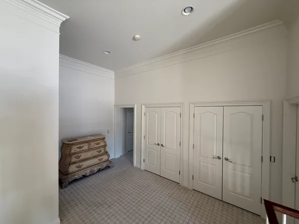 Light-colored upstairs walls above two white closet-door pairs and a wood dresser