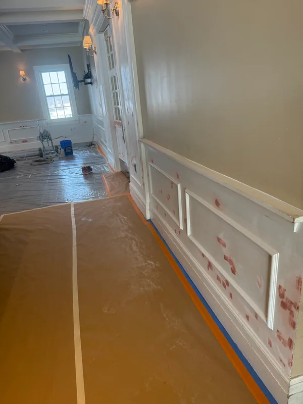 White wall panels with small reddish filler patches above a paper-covered floor